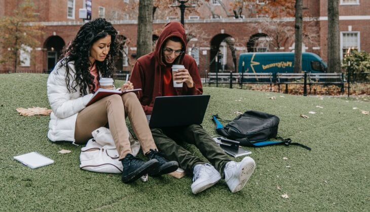 Studierende, die im Park sitzen und lernen