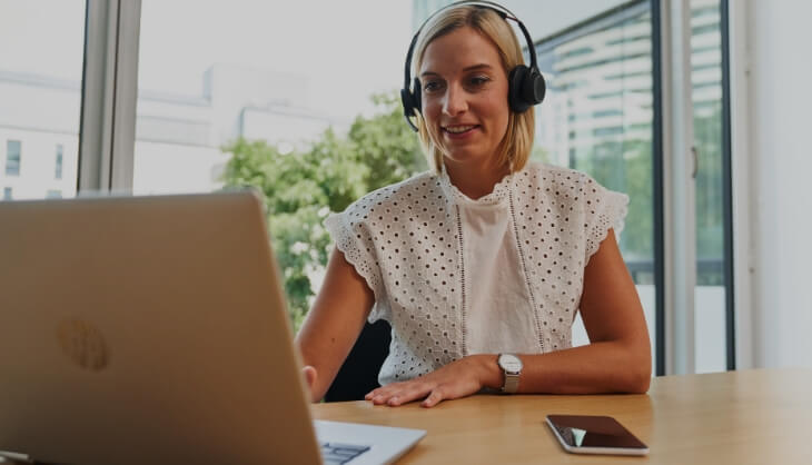 Woman working with headset on laptop